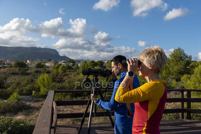 Pareja joven de observadores de aves usando prismáticos y telescopio, Calpe, provincia de Alicante, Costa Blanca, España - foto de stock