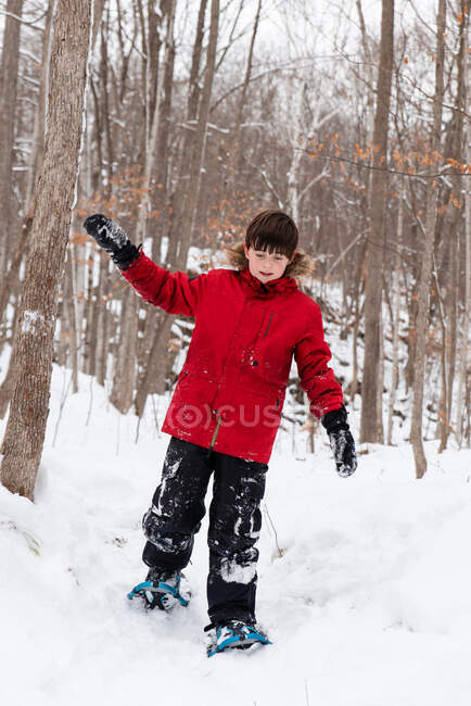 Jovem rapaz snowshoeing na floresta em um dia de inverno nevado. — Fotografia de Stock
