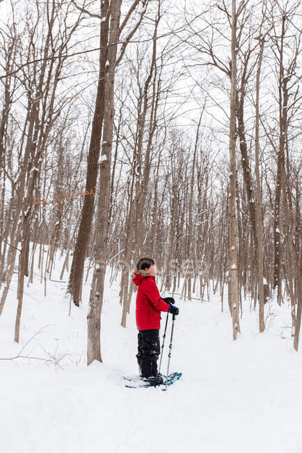 Giovane ragazzo ciaspolata nei boschi in una giornata invernale innevata. — Foto stock