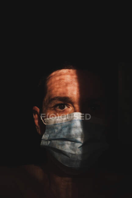 Hombre con máscara en las sombras, protección covid - foto de stock