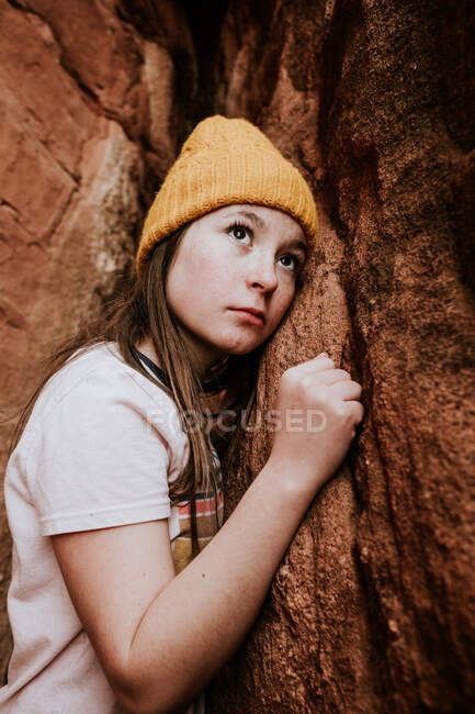 Vertikales Porträt eines frühpubertären Mädchens, das zu Felsen aufschaut — Stockfoto
