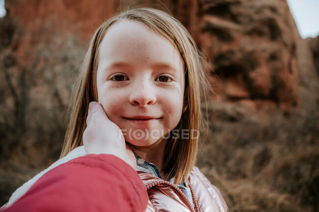 Glückliches junges Mädchen lächelt, während Mama das Gesicht berührt — Stockfoto