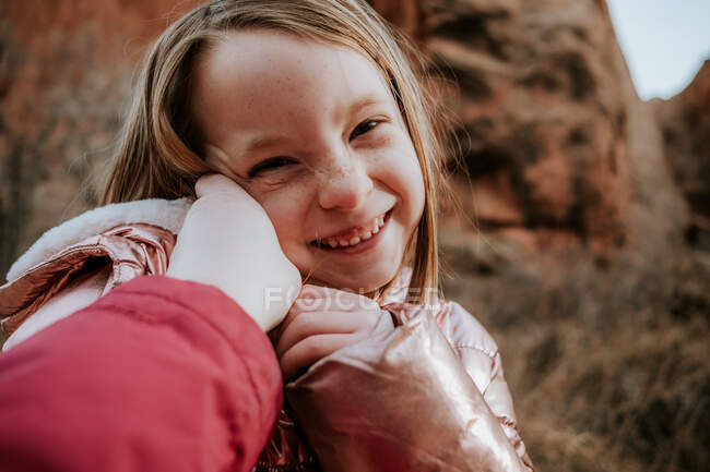 Glückliches junges Mädchen lacht, während Mama ihr Gesicht berührt — Stockfoto