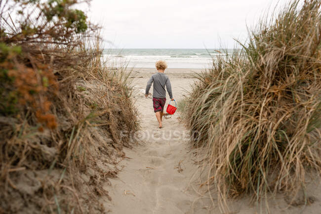Bambino con capelli ricci biondi che gioca nella piscina rocciosa in Nuova Zelanda — Foto stock
