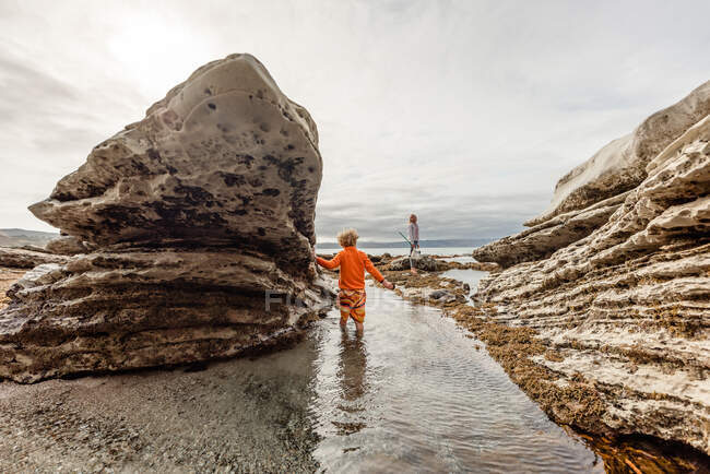 Fratelli che esplorano piscine rocciose in Nuova Zelanda in una giornata nuvolosa — Foto stock
