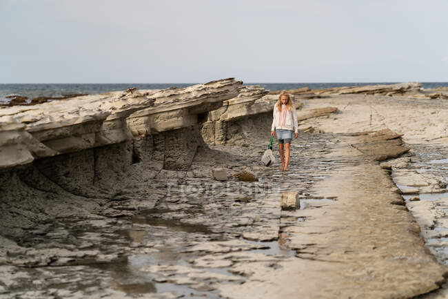 Frontansicht eines Mädchens, das mit Netz an felsiger Küste in Neuseeland spaziert — Stockfoto