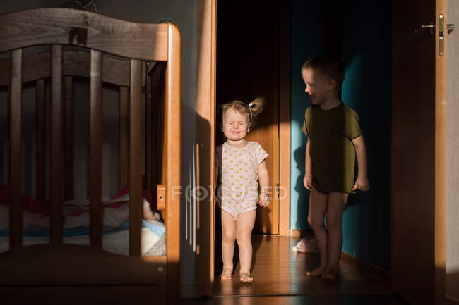 Fratello e sorella giocano a casa. la ragazza strizza gli occhi al sole il — Foto stock