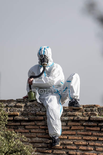 Человек в костюме вируса эпинефрина и противогаз на лице на фоне города — стоковое фото