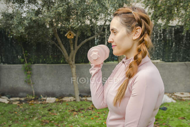 Young woman doing exercises with dumbbells in the park — Stock Photo