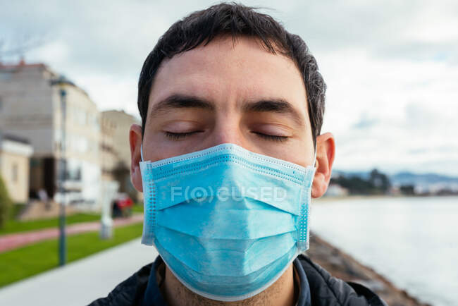 Giovane uomo per strada indossando una maschera con gli occhi chiusi — Foto stock