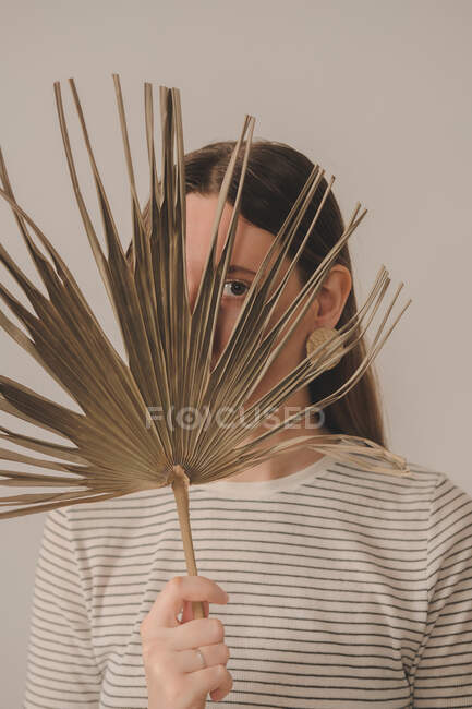 Retrato de una mujer mirando a través de una hoja de palma. Joven caucásico - foto de stock
