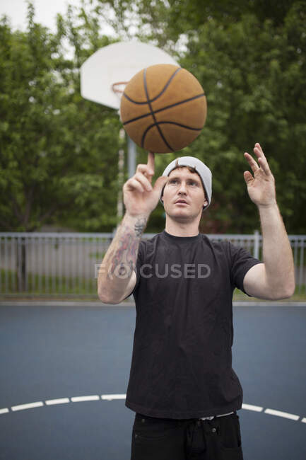 Jovem atleta masculino segurando bola na quadra de basquete tentando girá-lo no dedo, Montreal, Quebec, Canadá — Fotografia de Stock