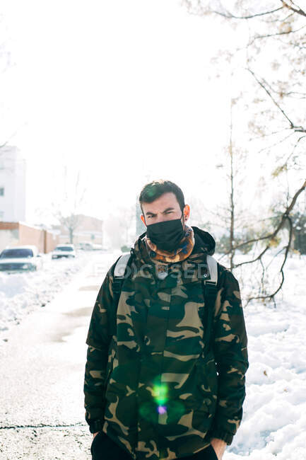 Giovane uomo che indossa una maschera protettiva medica nella neve — Foto stock