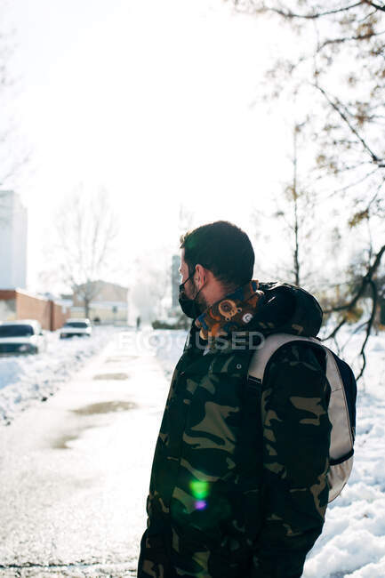 Young man wearing a medical protective mask in the snow — Stock Photo
