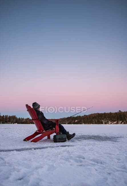 Ragazzo pesca mentre seduto sulla neve — Foto stock