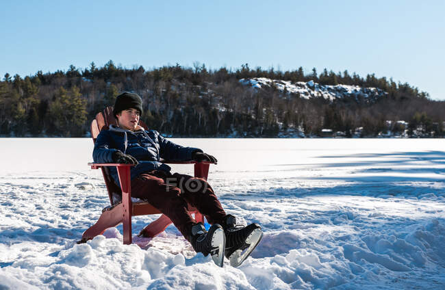 Teen boy taking a break from skating on outdoor rink on winter day. — Stock Photo