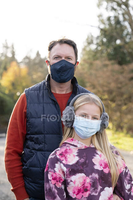 Hombre y chica joven con mascarillas al aire libre en un día de otoño en Seattle - foto de stock