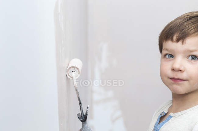 3 años lindo niño con rodillo de pintura en la mano - foto de stock