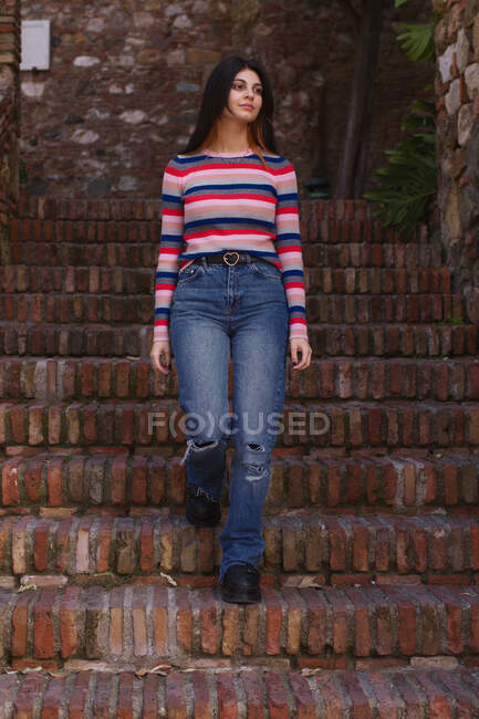 Natural young woman going down stairs of an old urban construction — Stock Photo