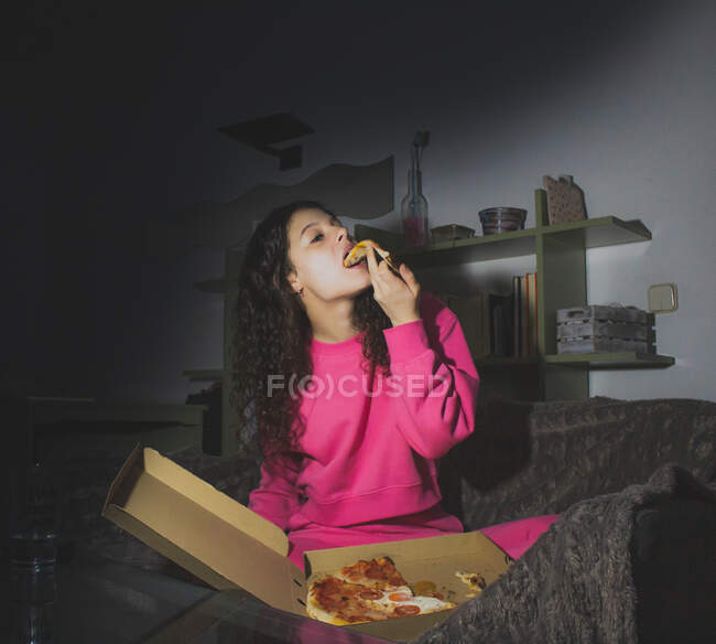 Une jeune fille assise seule et mangeant de la pizza — Photo de stock