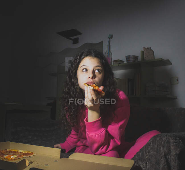 Una giovane ragazza seduta da sola e mangiare pizza — Foto stock