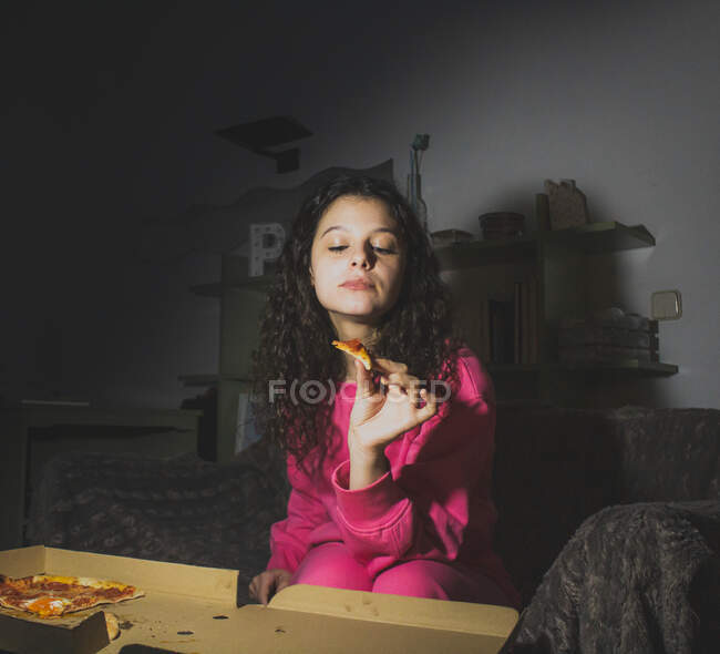 Uma jovem sentada sozinha e comendo pizza — Fotografia de Stock