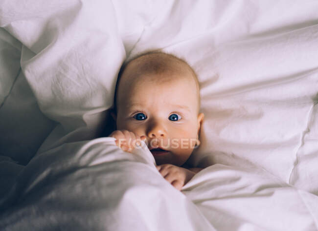 Un bebé en la cama - foto de stock