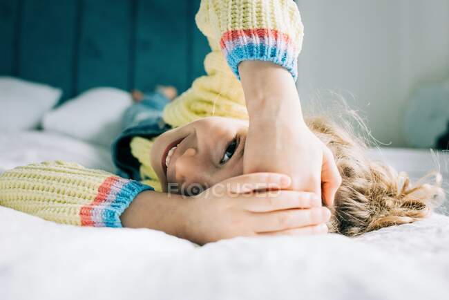 Freimütiges Porträt eines jungen Mädchens, das lachend zu Hause liegt — Stockfoto