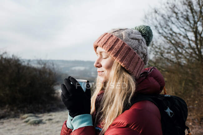 Женщина улыбается, держа горячий напиток, наслаждаясь холодным воздухом в Великобритании — стоковое фото