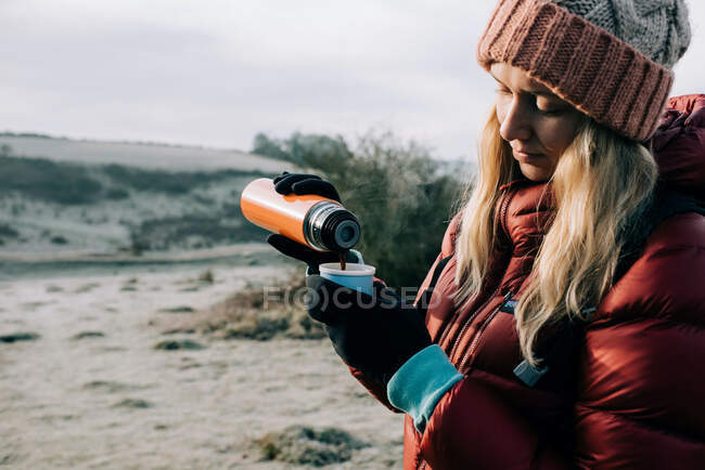 Жінка заливає гарячу чашку кави надворі під час прогулянки в Англії. — стокове фото