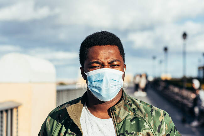 Portrait of a black boy with face mask. Dressed in military jacket. — Stock Photo