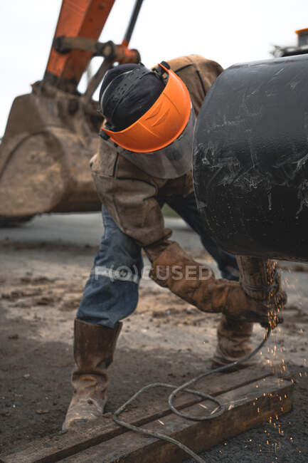 Человек, работающий на водопроводной трубе на открытом воздухе в защитной одежде — стоковое фото