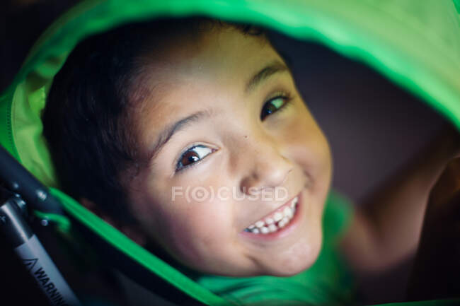 Rapaz a olhar através de um carrinho verde — Fotografia de Stock