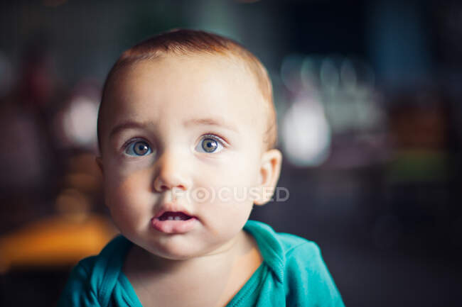 Bambino con occhi nocciola e tutina verde. — Foto stock