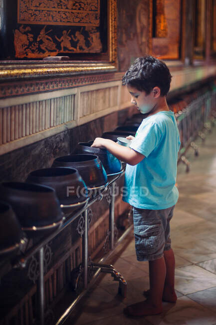 Barefoot boy visiting a Buddhist temple in Bangkok, Thailand. — Stock Photo