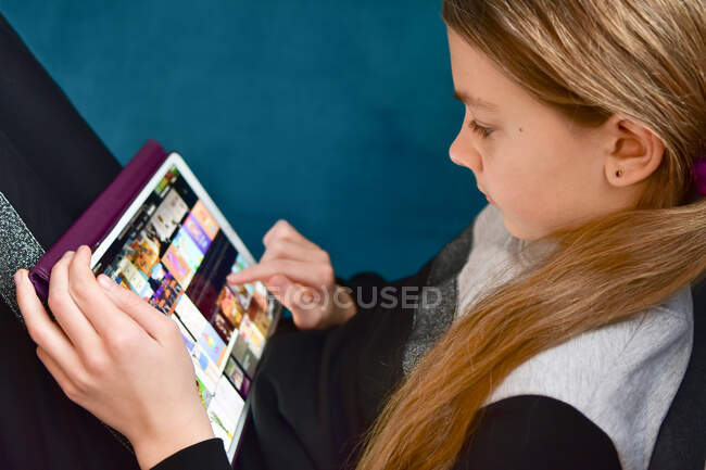 La niña realiza tareas en la tableta durante la cuarentena. - foto de stock