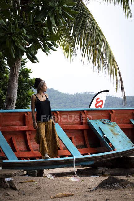 Красивая молодая женщина в заброшенной лодке на пляже острова — стоковое фото