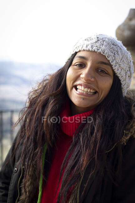 Красива молода жінка, що посміхається з пірсингами в парку з зимовим капелюхом. — стокове фото