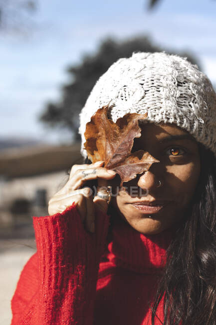 A beautiful woman holding a leaf in autumn season with winter hat — Stock Photo