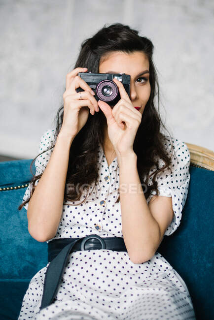 Молодая женщина в платье в стиле ретро с камерой на сером фоне — стоковое фото