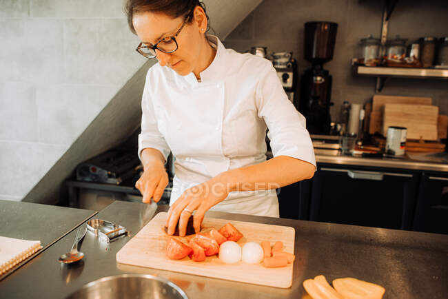 Femme chef coupant des légumes dans la cuisine du restaurant — Photo de stock
