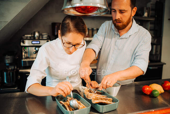 Couple de chefs travaillant ensemble tout en préparant la nourriture au restaurant — Photo de stock