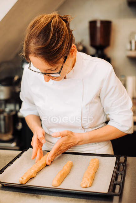 Женщина-повар кладет тесто на поднос, чтобы испечь печенье — стоковое фото