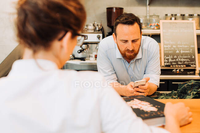 Restaurant lifestyle. Male chef using his phone, standing at bar — Stock Photo