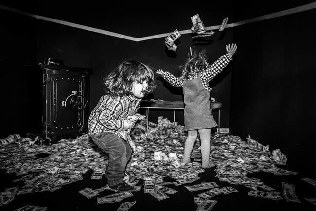 Little girls having fun while throwing money bills in the air. Money a — Stock Photo