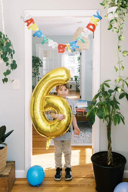 Kleiner Junge an seinem Geburtstag mit großem goldenen Luftballon in den Händen — Stockfoto
