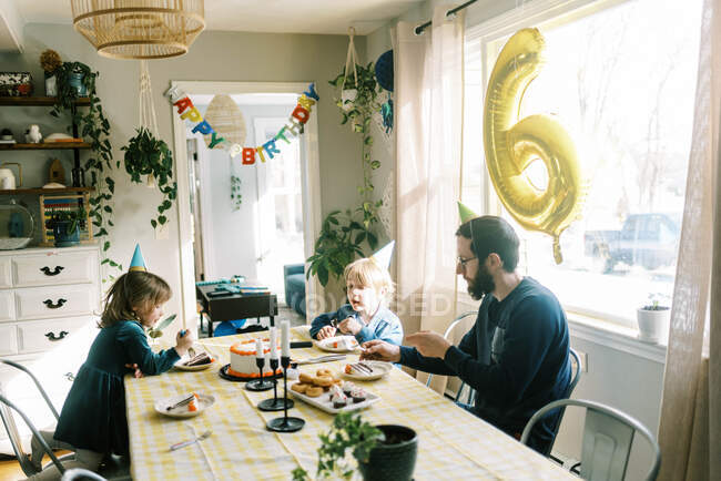 Маленькая семья ест праздничный торт за столом и празднует — стоковое фото