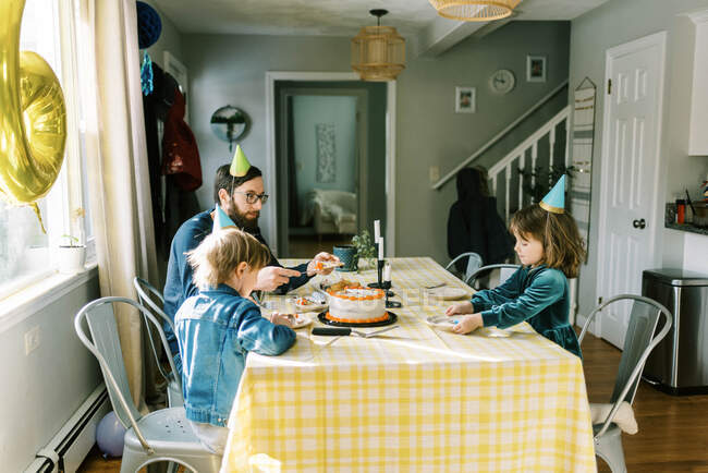 Uma pequena família comendo bolo de aniversário na mesa e comemorando — Fotografia de Stock