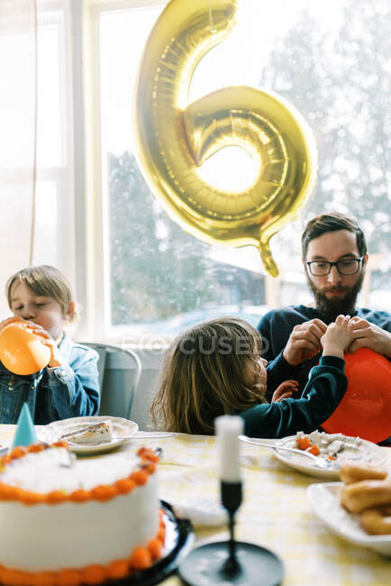 Father and kids together while playing with birthday balloons — Stock Photo