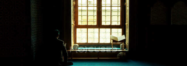 Человек, читающий Коран в мечети, месяц рамадан, мусульманин — стоковое фото